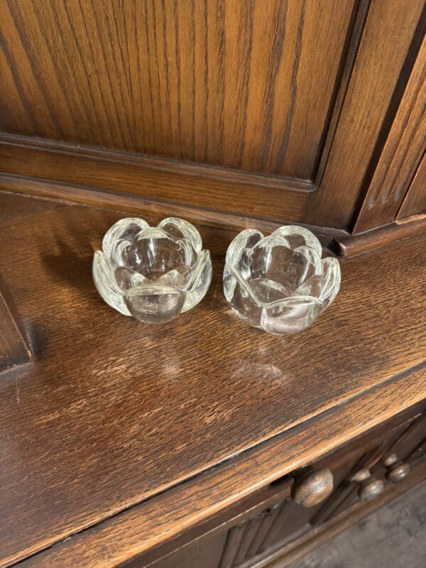 A pair of glass candle holders sitting on top of a wooden table.