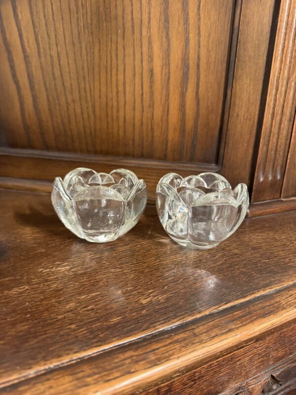 A pair of glass candle holders sitting on top of a wooden table.