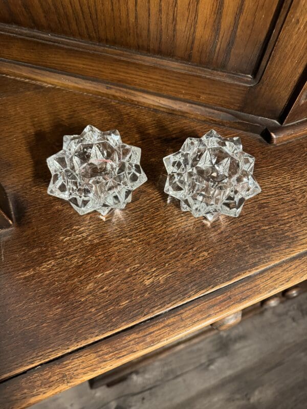 A pair of glass candle holders sitting on top of a wooden table.