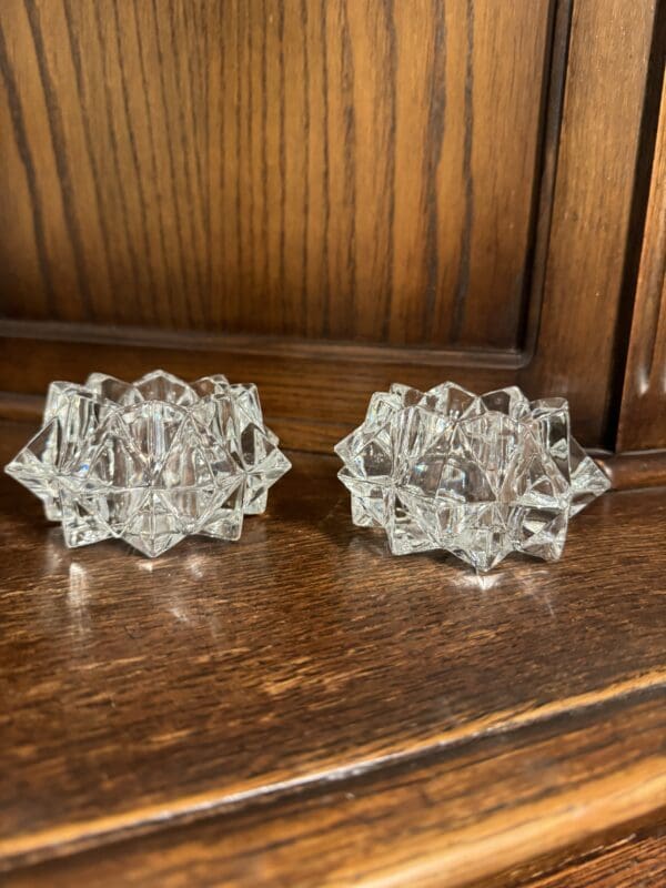 A pair of glass candle holders on top of a wooden table.