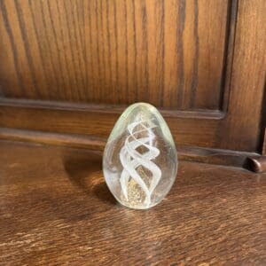 A glass egg sitting on top of a wooden table.
