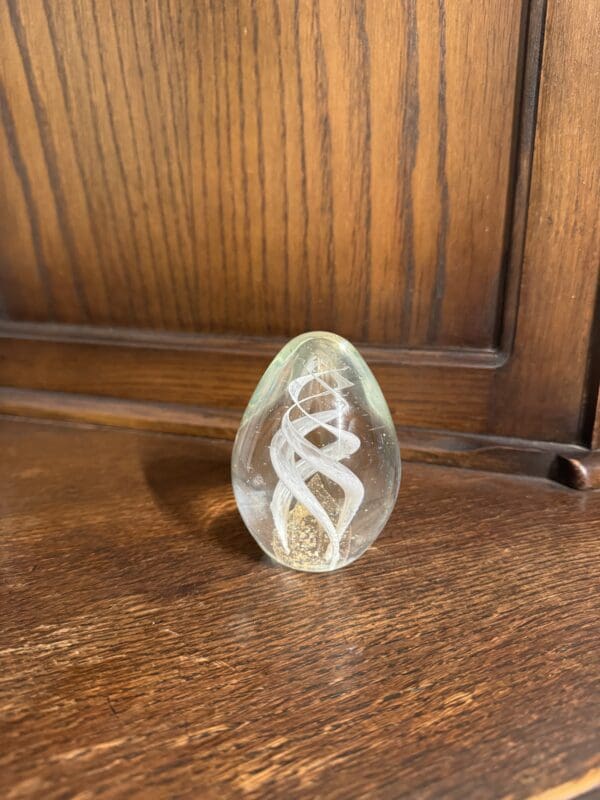 A glass egg sitting on top of a wooden table.