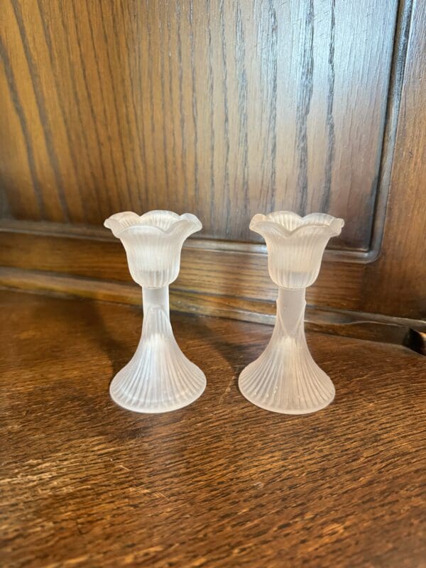 Two frosted glass candle holders on a table.