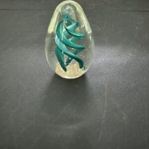 A glass sculpture of a green spiral on top of a table.