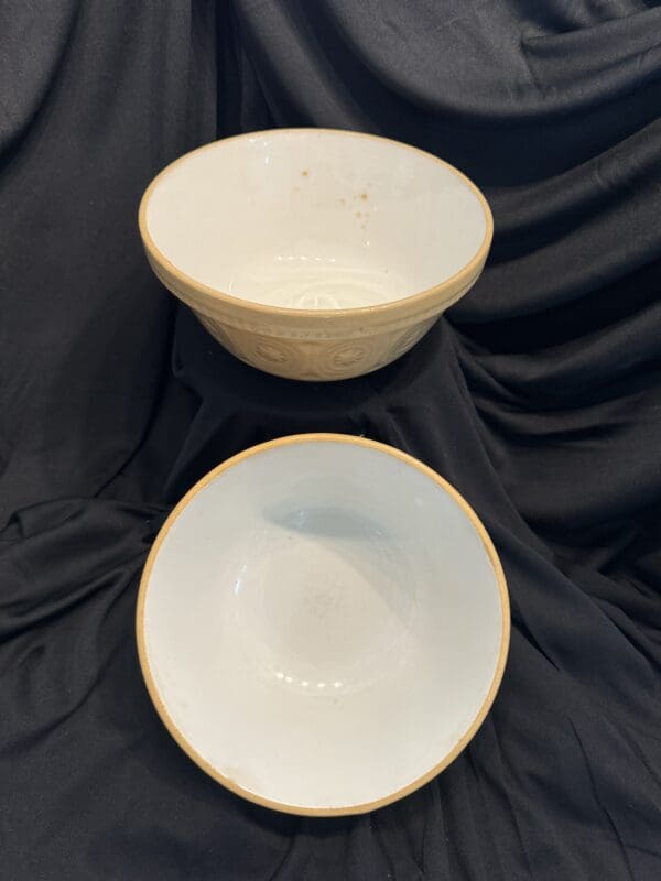 Two bowls are sitting on a black cloth.