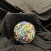 A ball is sitting on the ground with swirls of colors.