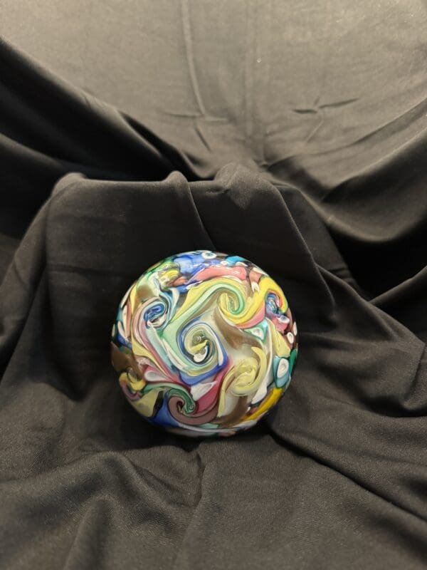 A ball is sitting on the ground with swirls of colors.