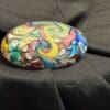 A rock with many colors on it sitting on top of a bed.