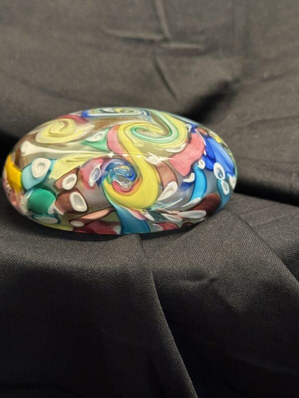 A rock with many colors on it sitting on top of a bed.