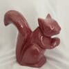 A red squirrel statue sitting on top of a table.