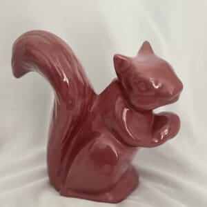A red squirrel statue sitting on top of a table.