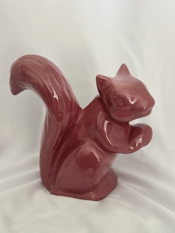 A red squirrel statue sitting on top of a table.