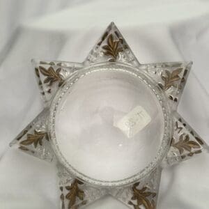 A glass star with gold trim on top of white cloth.