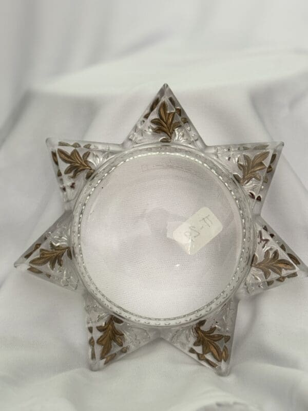 A glass star with gold trim on top of white cloth.