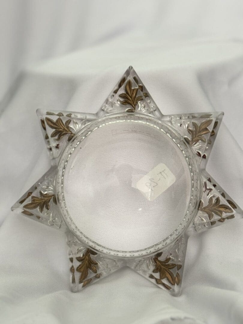 A glass star with gold trim on top of white cloth.