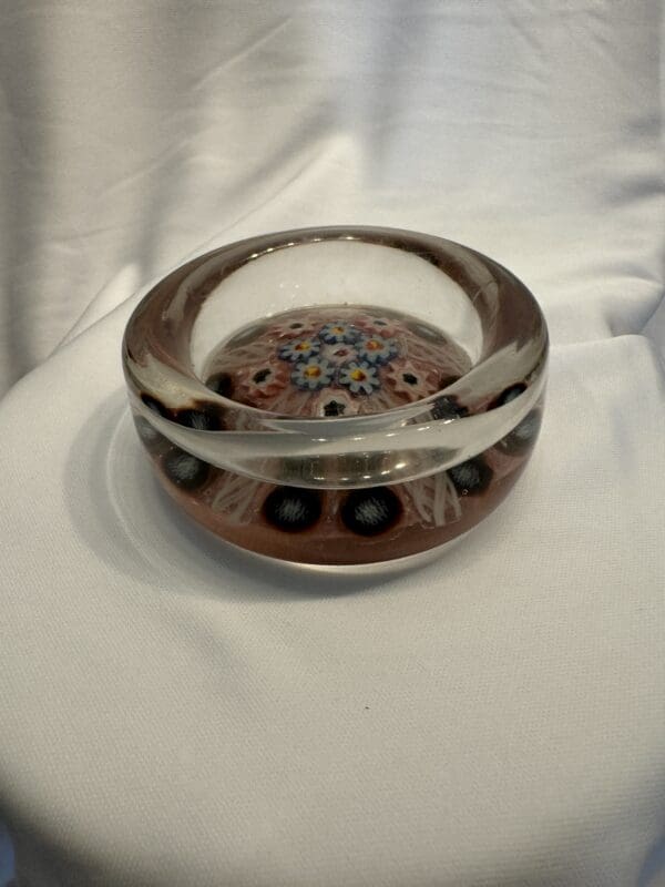 A glass bowl with brown and black design on top of white cloth.