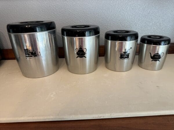 A group of five canisters on top of a counter.