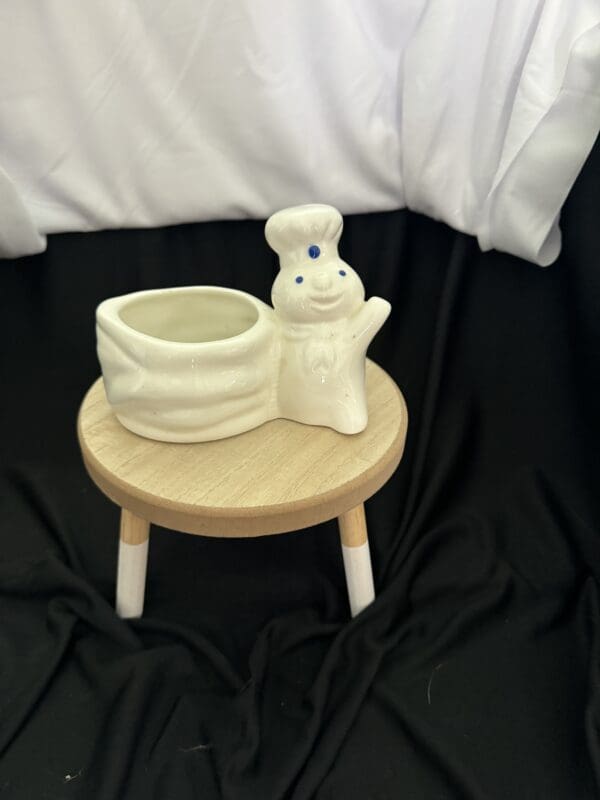 A small stool with a white ceramic pot on top of it.