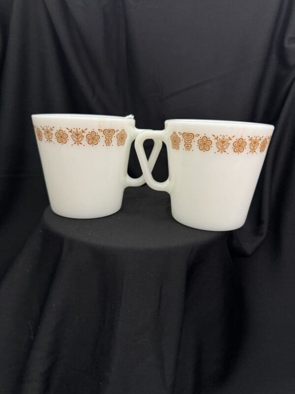 Two white cups sitting on top of a black table.