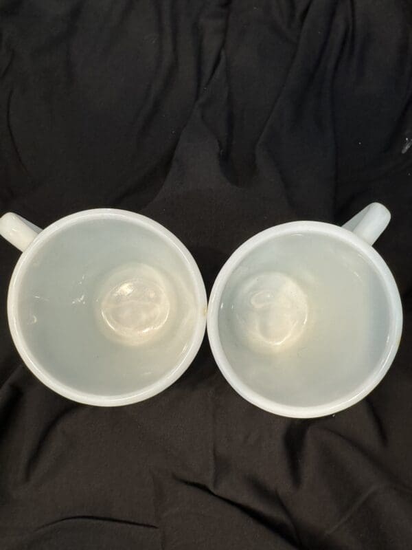 Two white cups sitting on top of a black table.