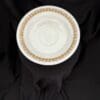 A white plate with brown trim on top of black cloth.