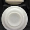 A stack of white plates and bowls on top of black cloth.