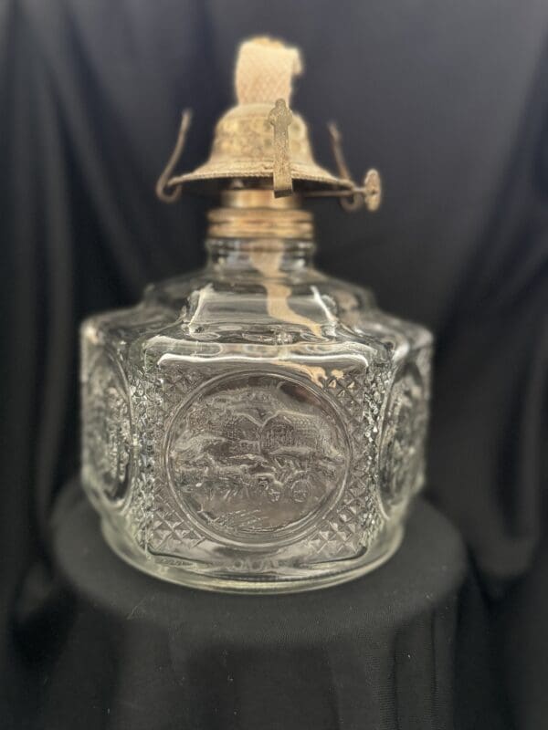 A glass bottle with a brass top on a black table.