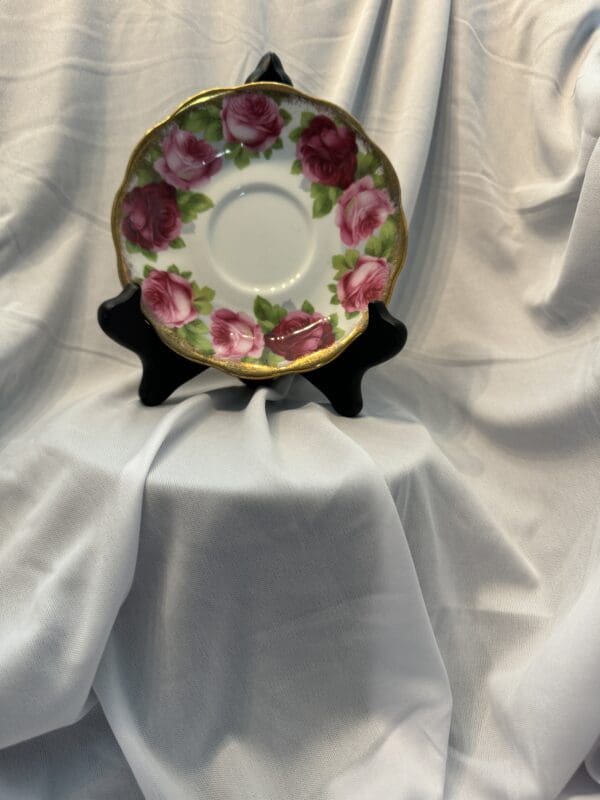 A plate with roses on it is sitting in front of a white cloth.