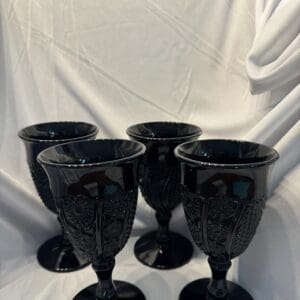 A group of four black glasses sitting on top of a table.