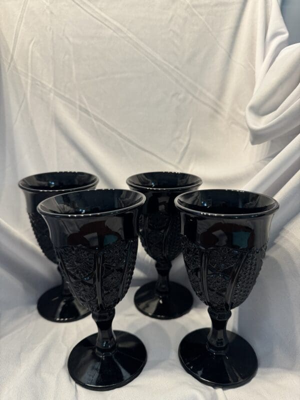 A group of four black glasses sitting on top of a table.