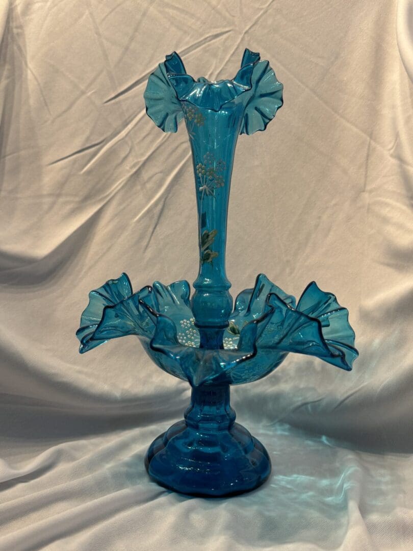 A blue glass vase with ruffle design on top of it.