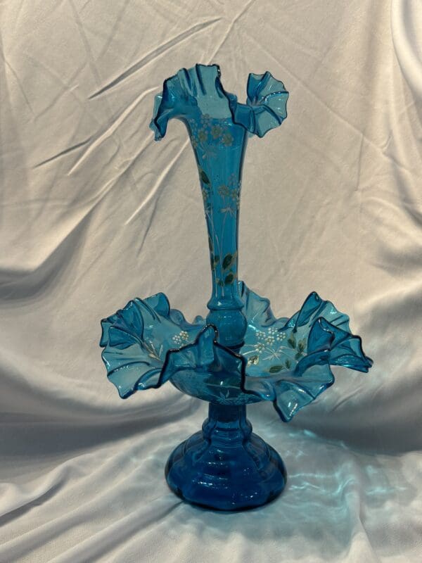 A blue glass vase with ruffled edges on top of it.