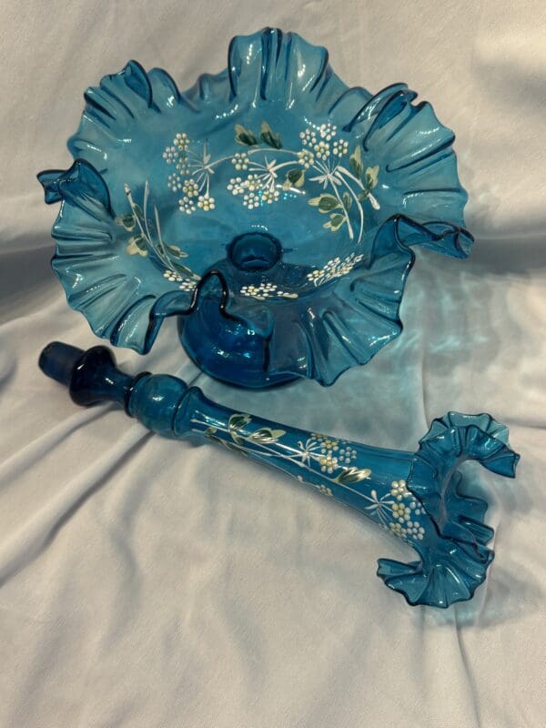 A blue umbrella and tea pot on top of white cloth.