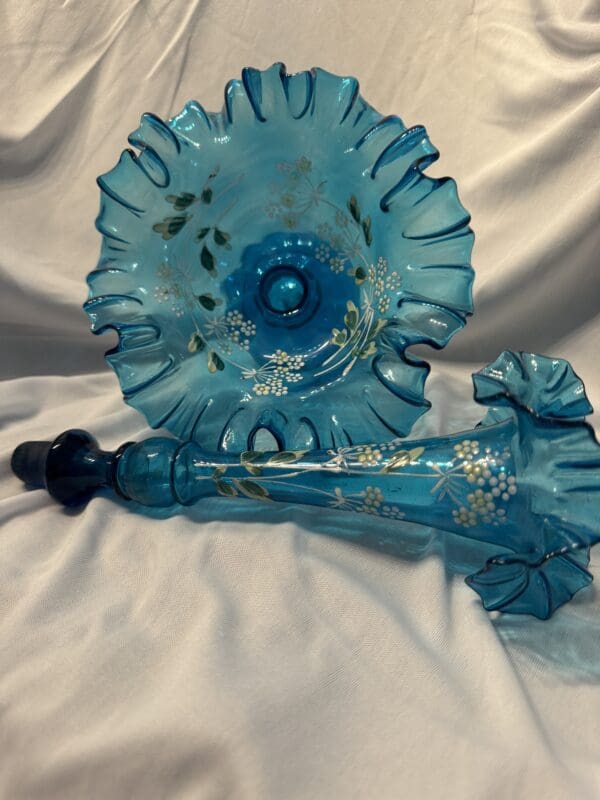 A blue glass vase and bowl sitting on top of a white table.