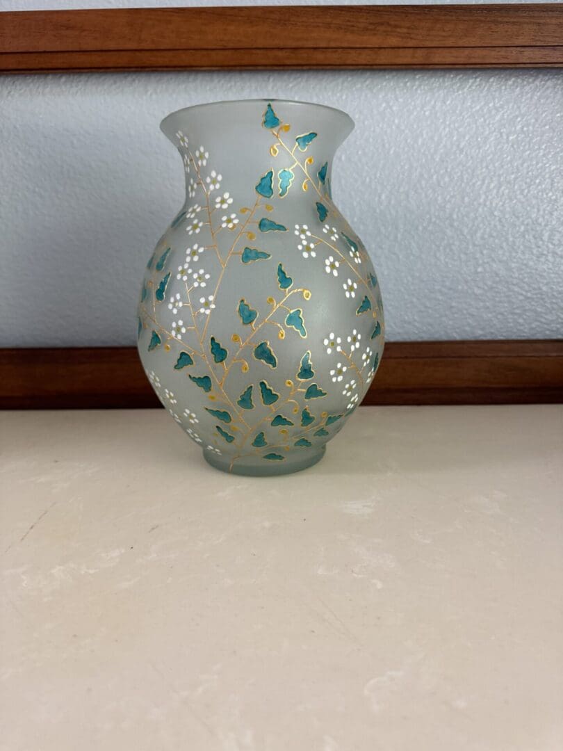 A glass vase with flowers painted on it