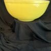 A yellow bowl sitting on top of black cloth.