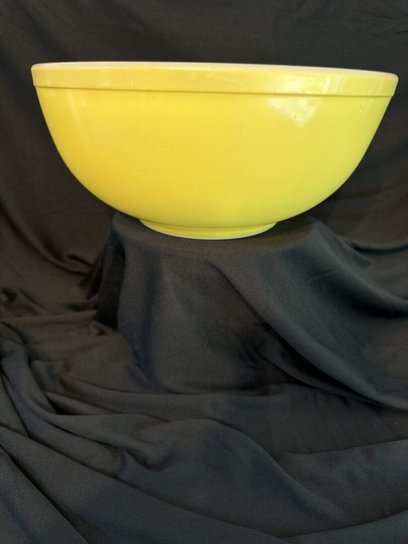 A yellow bowl sitting on top of black cloth.