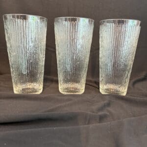 Three tall glasses are sitting on a table.