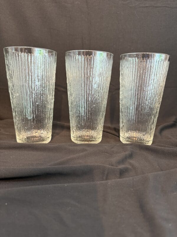 Three tall glasses are sitting on a table.