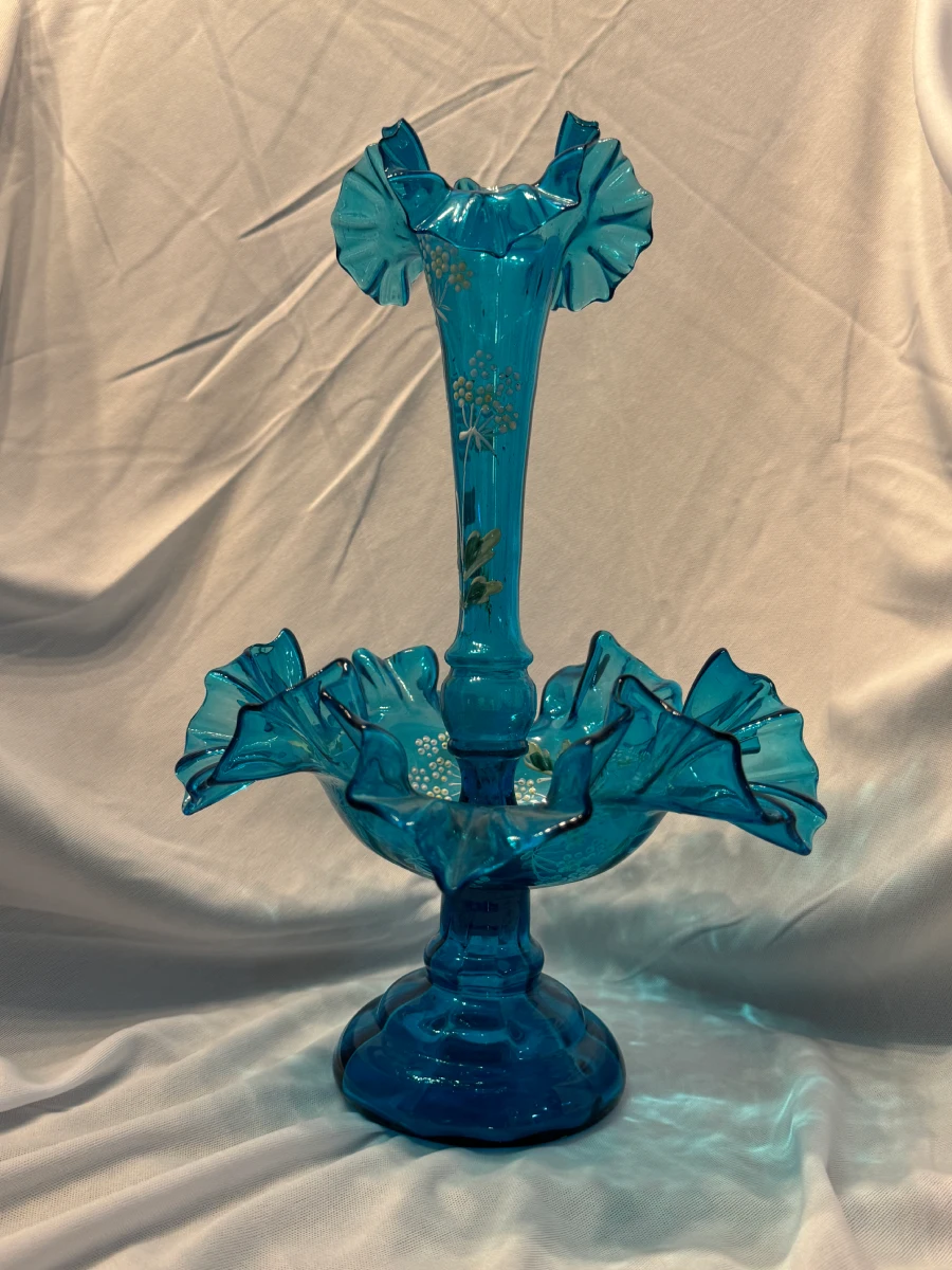 A blue glass vase with ruffles on top of it.