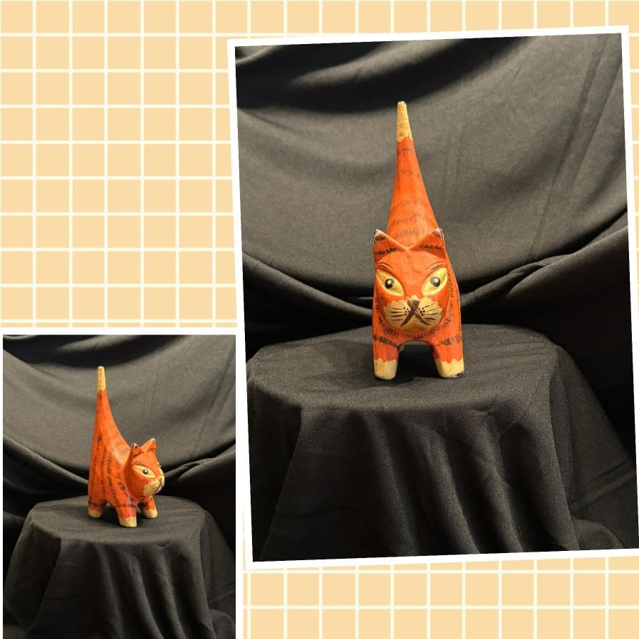 A cat with an orange hat on sitting on top of a table.