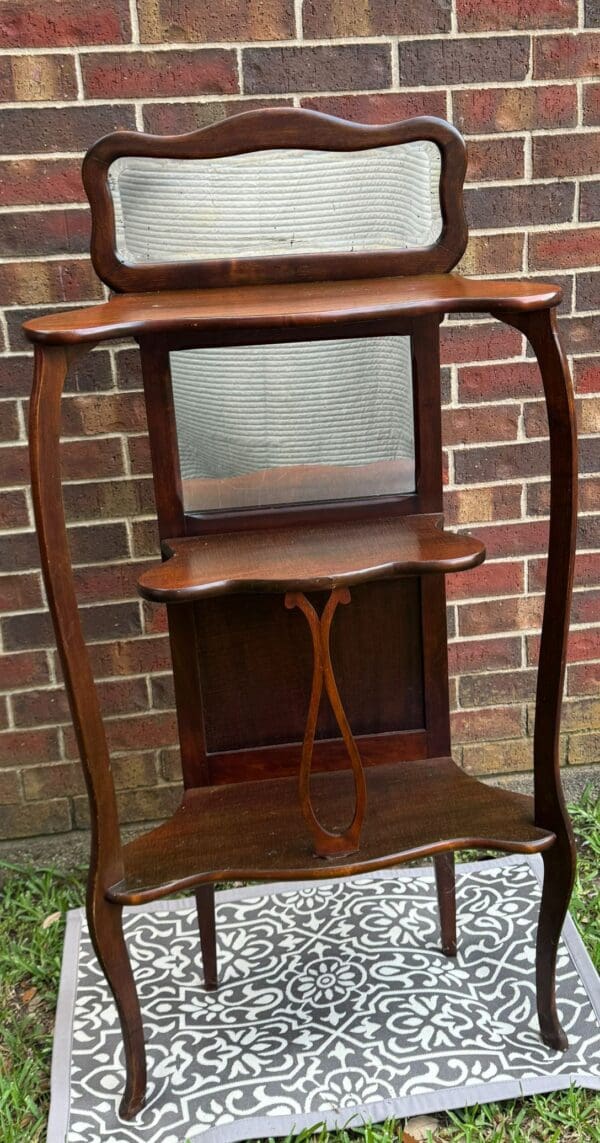 A wooden shelf with a mirror and two shelves.