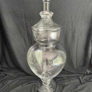A large glass vase with a metal top.