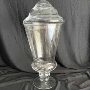 A large glass vase with a lid on top of it.