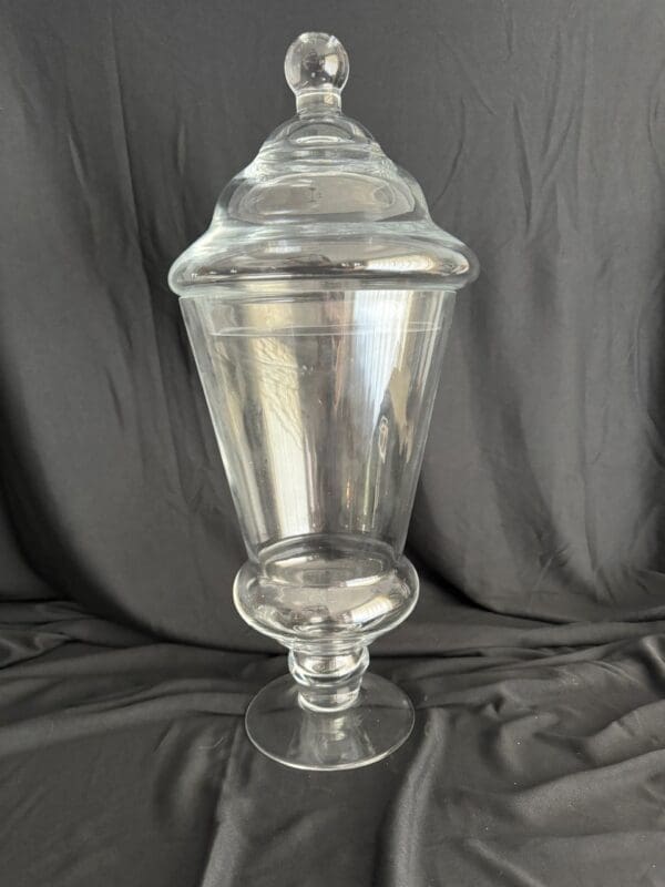 A large glass vase with a lid on top of it.