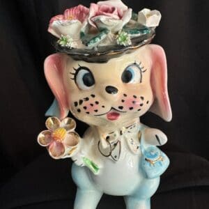 A ceramic dog with flowers on top of it's head.