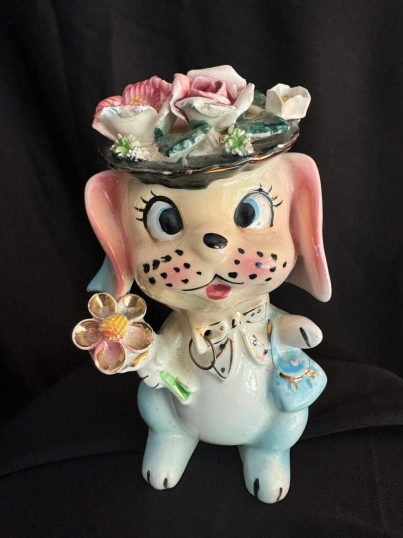 A ceramic dog with flowers on top of it's head.