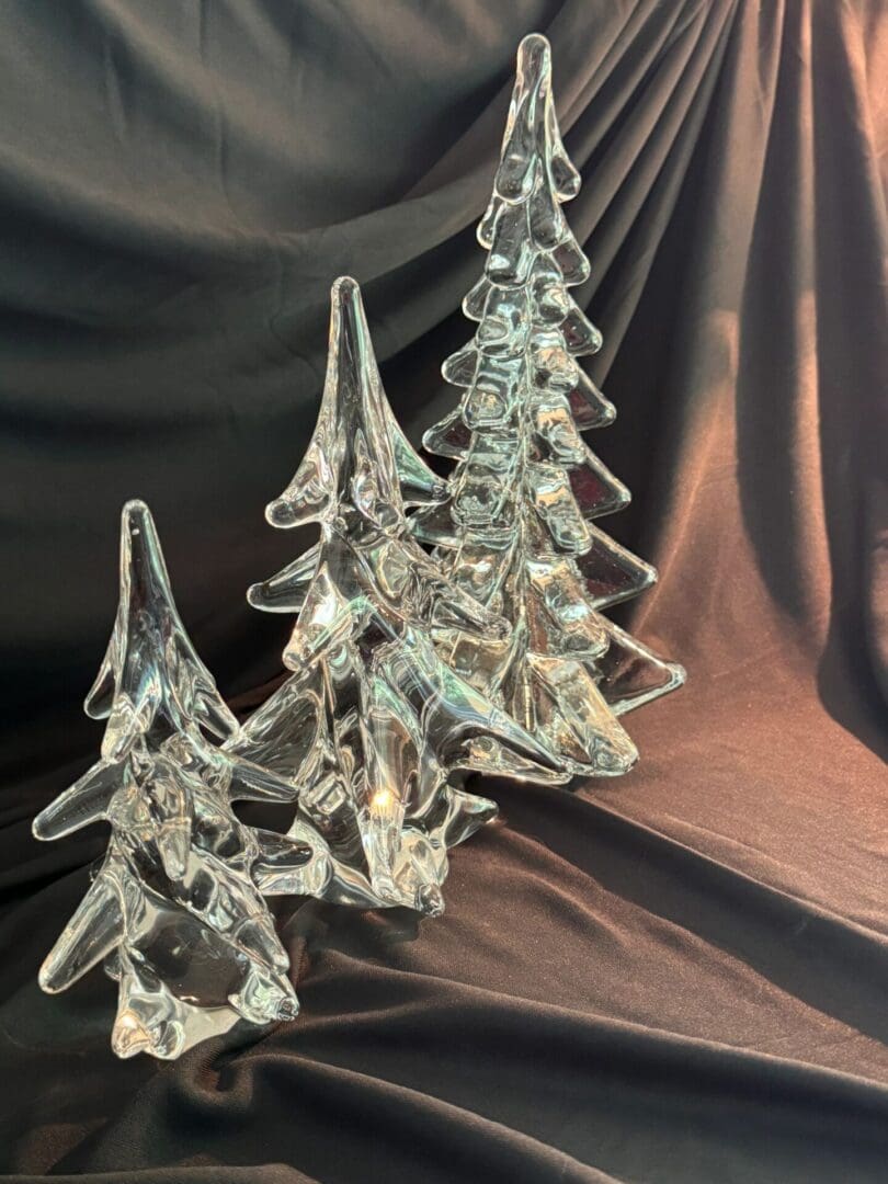 A group of three glass trees sitting on top of a table.