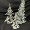 A group of three glass trees on top of black cloth.