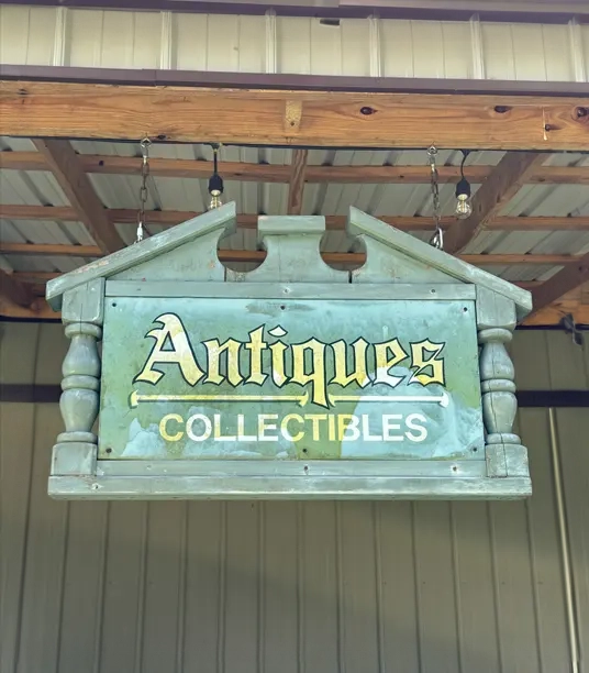 A sign hanging from the ceiling of an antiques store.